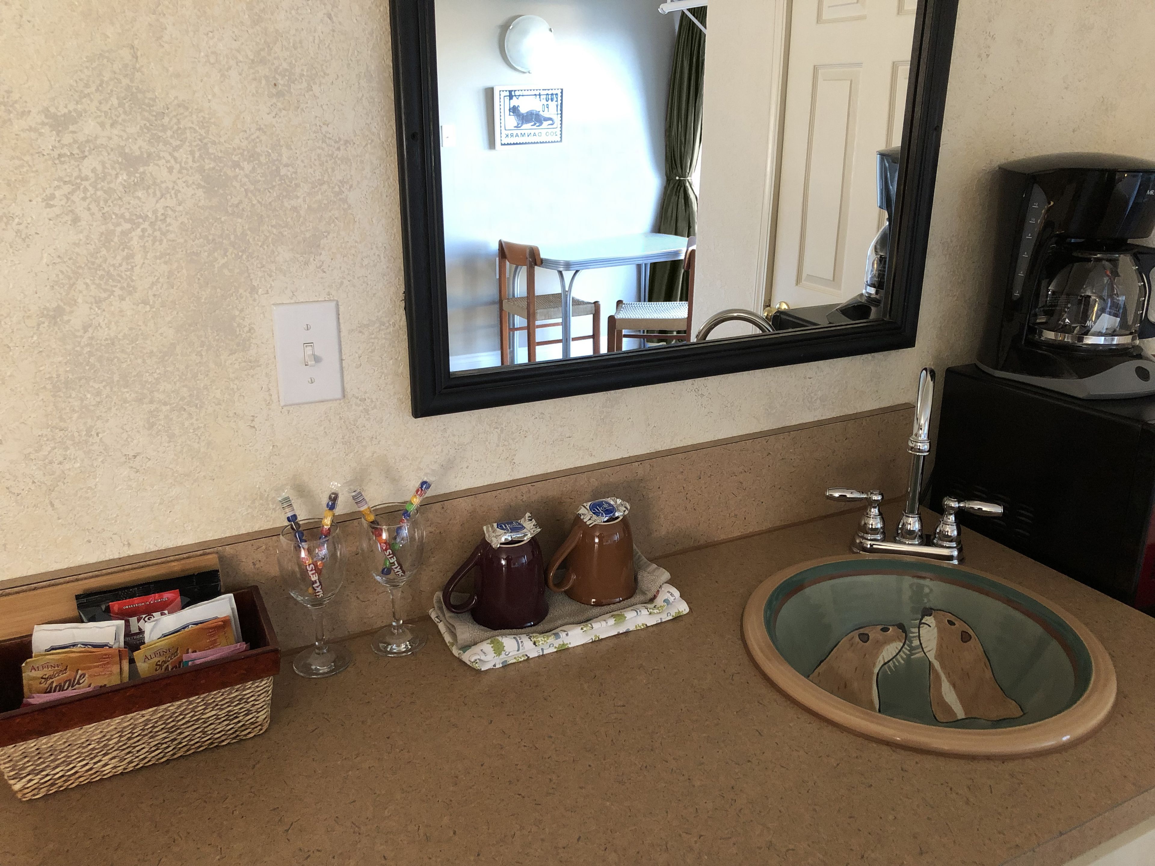 A bathroom with a sink, mirror, and coffee maker.