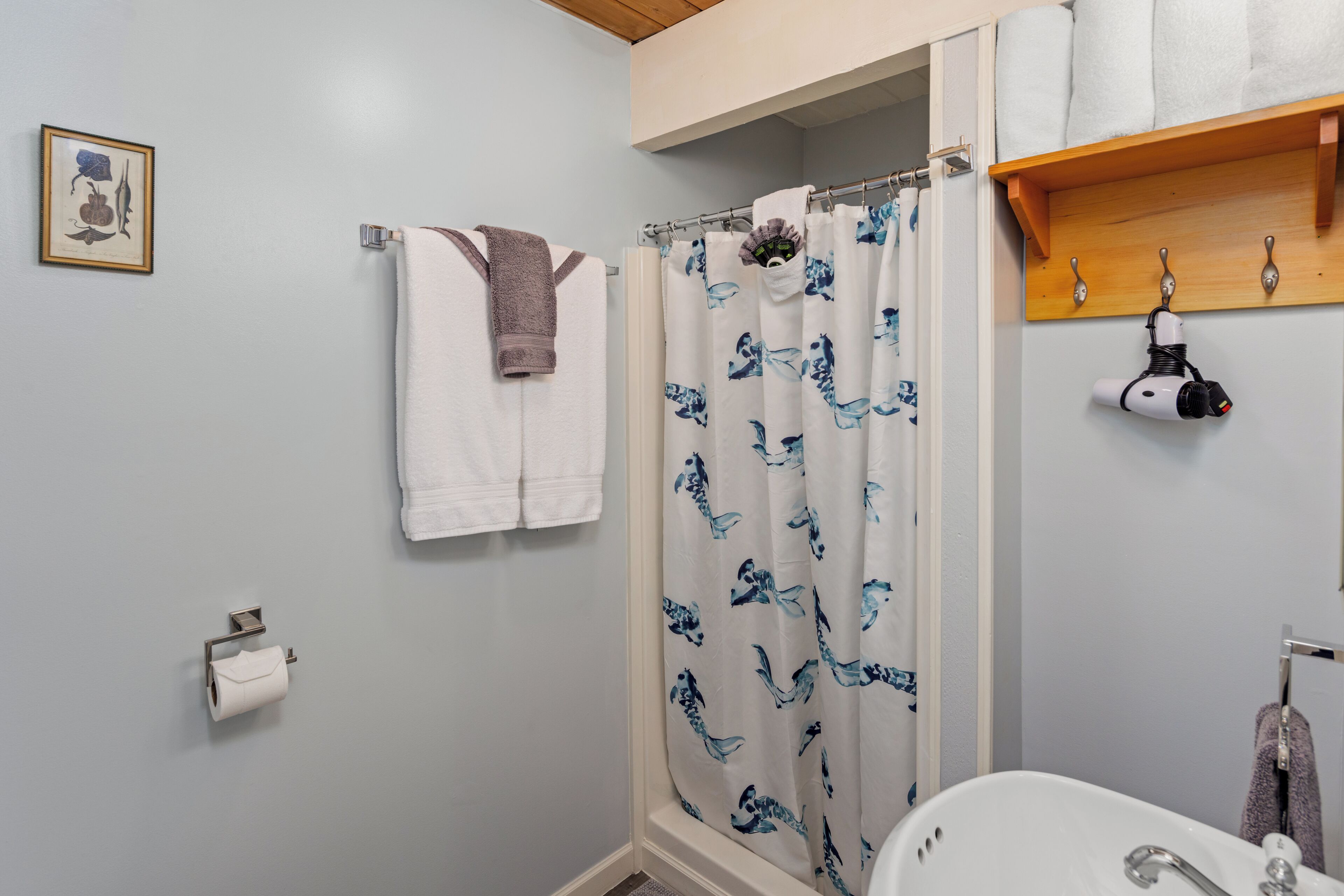 Ein Badezimmer mit Duschvorhang, Handtuchhalter, Toilettenpapierhalter und Waschbecken.