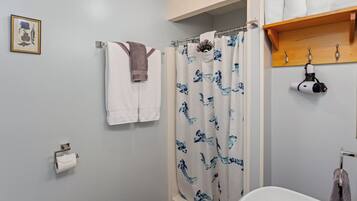 Ein Badezimmer mit Duschvorhang, Handtuchhalter, Toilettenpapierhalter und Waschbecken.