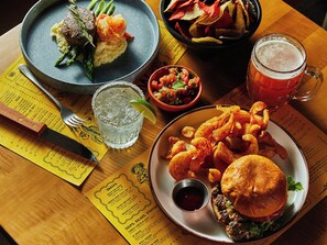 A table with a variety of dishes including a burger, fries, and a seafood dish, along with drinks and a menu. - Red Roof Inn PLUS+ Williams - Grand Canyon (Williams)