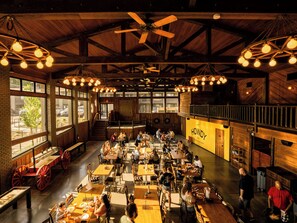 A spacious restaurant with high ceilings, exposed beams, and large windows. Tables are arranged for dining, and there is a visible staircase leading to an upper level. - Red Roof Inn PLUS+ Williams - Grand Canyon (Williams)