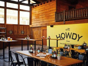 A restaurant interior with wooden walls, tables, chairs, and a yellow wall with the name 'HOWDY' and a horse logo. - Red Roof Inn PLUS+ Williams - Grand Canyon (Williams)