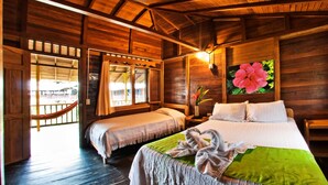 Una habitación de cabaña de madera con dos camas, una hamaca y un ventanal con vistas.