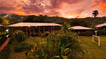 Um resort com vários edifícios, um jardim bem cuidado e vista para uma colina arborizada.