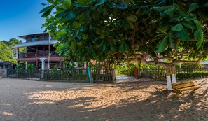 Ein Hotel mit zweistöckiger Bauweise, einem eingezäunten Garten und einer Sandstrandanlage.