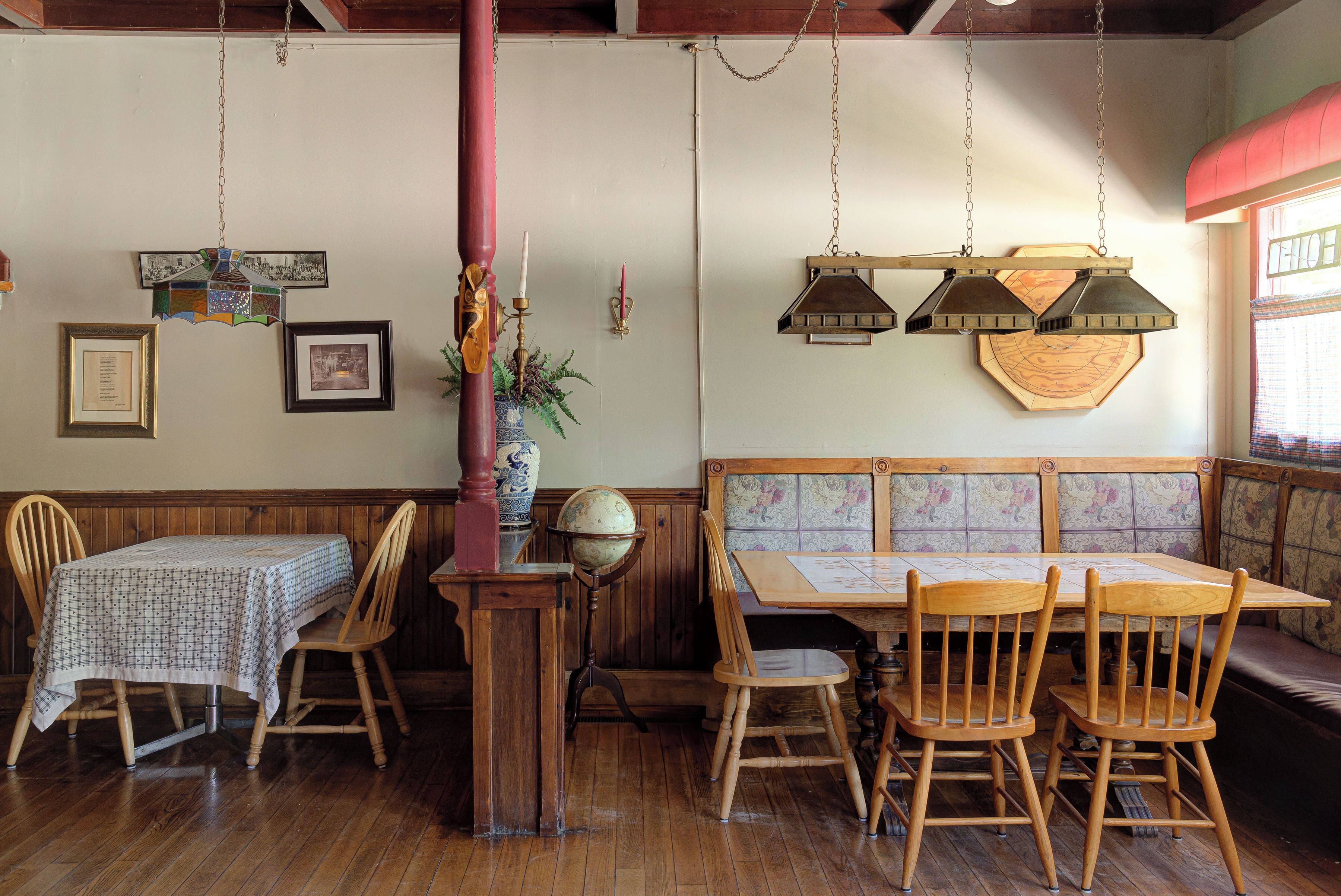 Comedor de madera con mesa y sillas, un globo en un soporte y faroles colgantes.