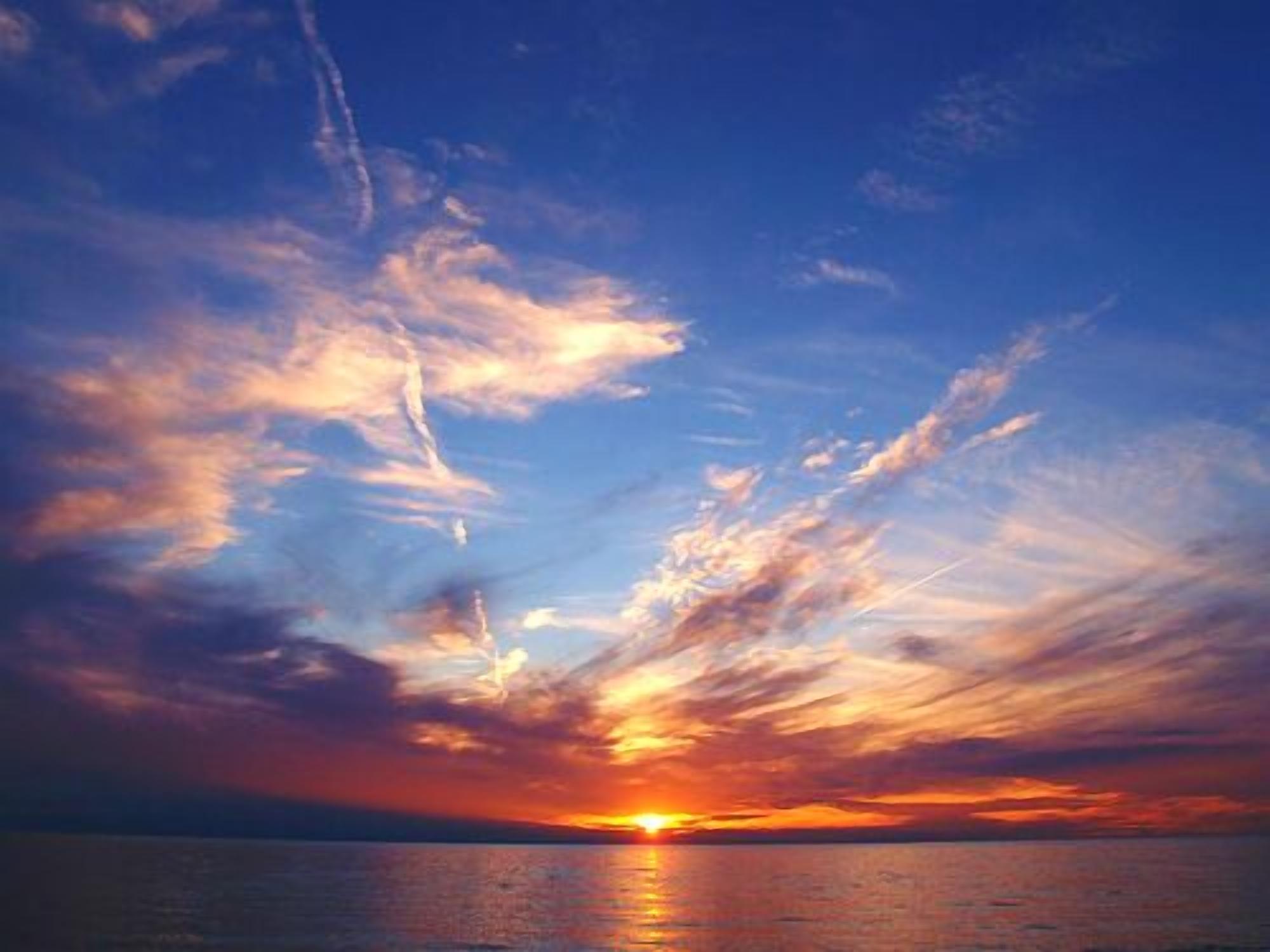 Ein Sonnenuntergang über ruhigem Meer mit klarem Horizont.