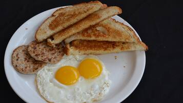 A plate with two fried eggs, two slices of toast, and two sausage patties.
