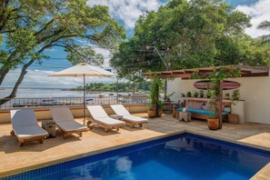 A poolside area with lounge chairs, a small table, and a seating area with cushions and plants. - OITI by Barracuda (Itacaré)