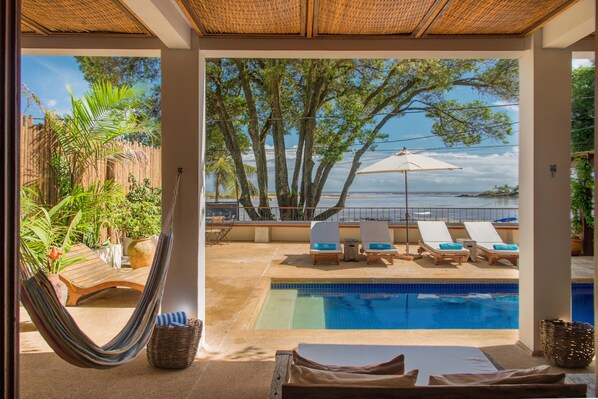 A poolside area with lounge chairs, a hammock, and a view of the sea. - OITI by Barracuda (Itacaré)