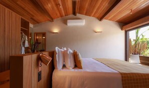 A bedroom with a wooden ceiling, a large bed with pillows, a nightstand, and a window with plants. - OITI by Barracuda (Itacaré)