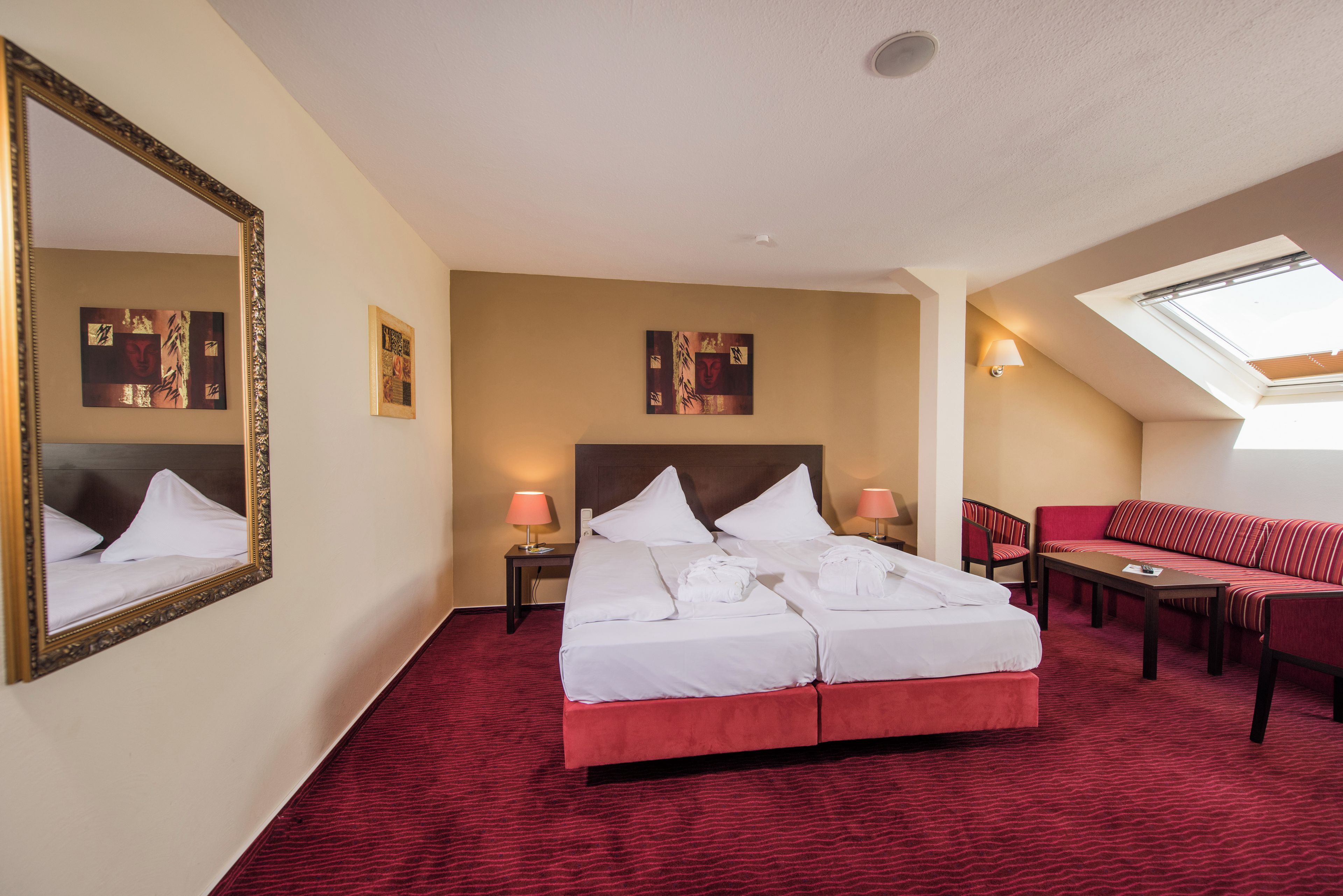 Une chambre d’hôtel avec un grand lit, un canapé, une table et une lucarne.