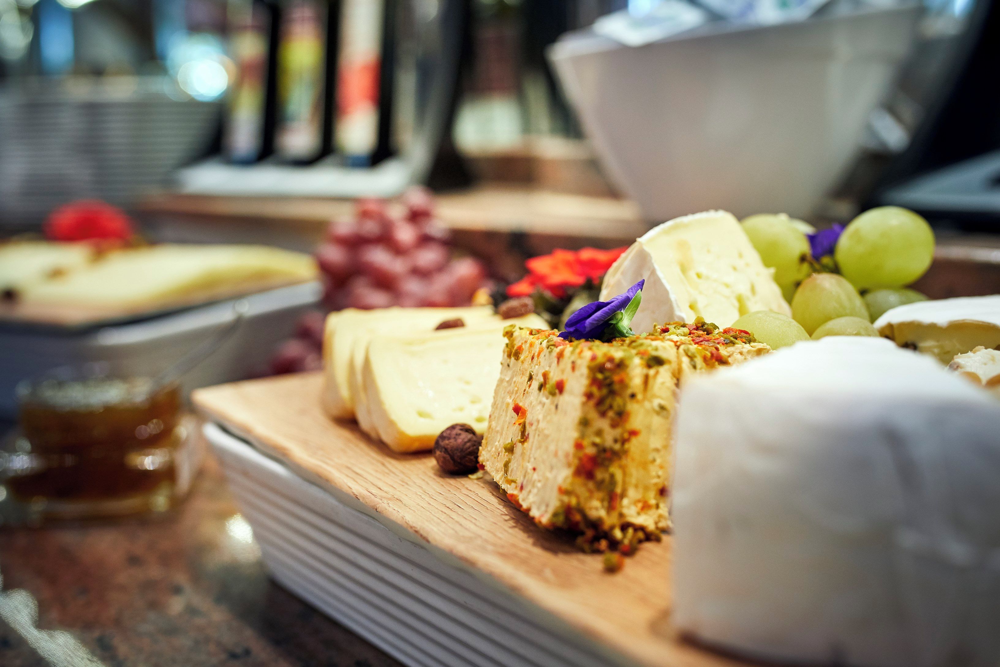 A variety of cheeses and fruits on a wooden board.
