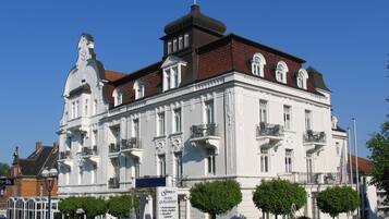 A historic building with a prominent clock tower, multiple balconies, and a sign indicating it is a hotel.