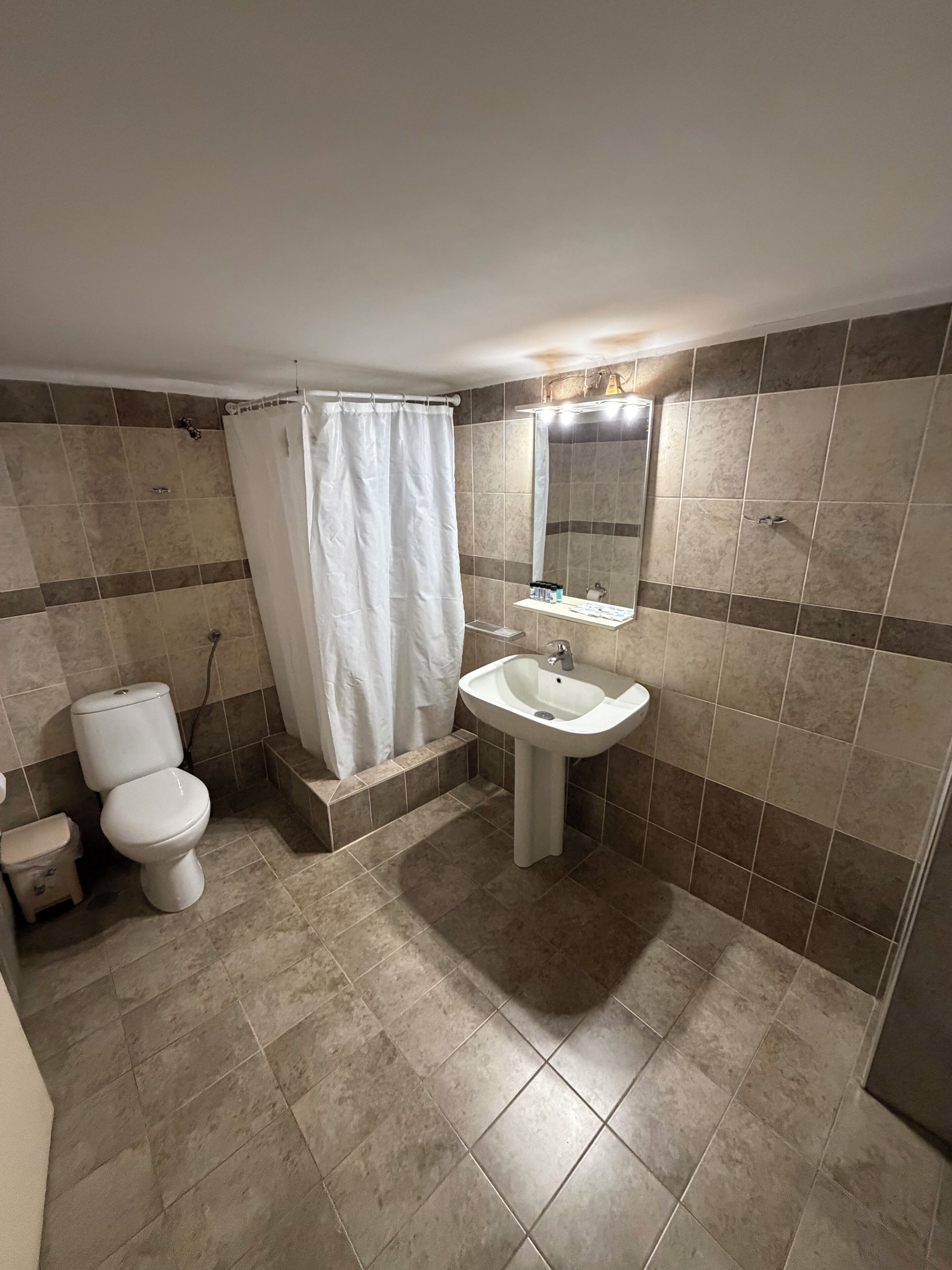 Baño con inodoro, lavamanos y cortina de ducha.