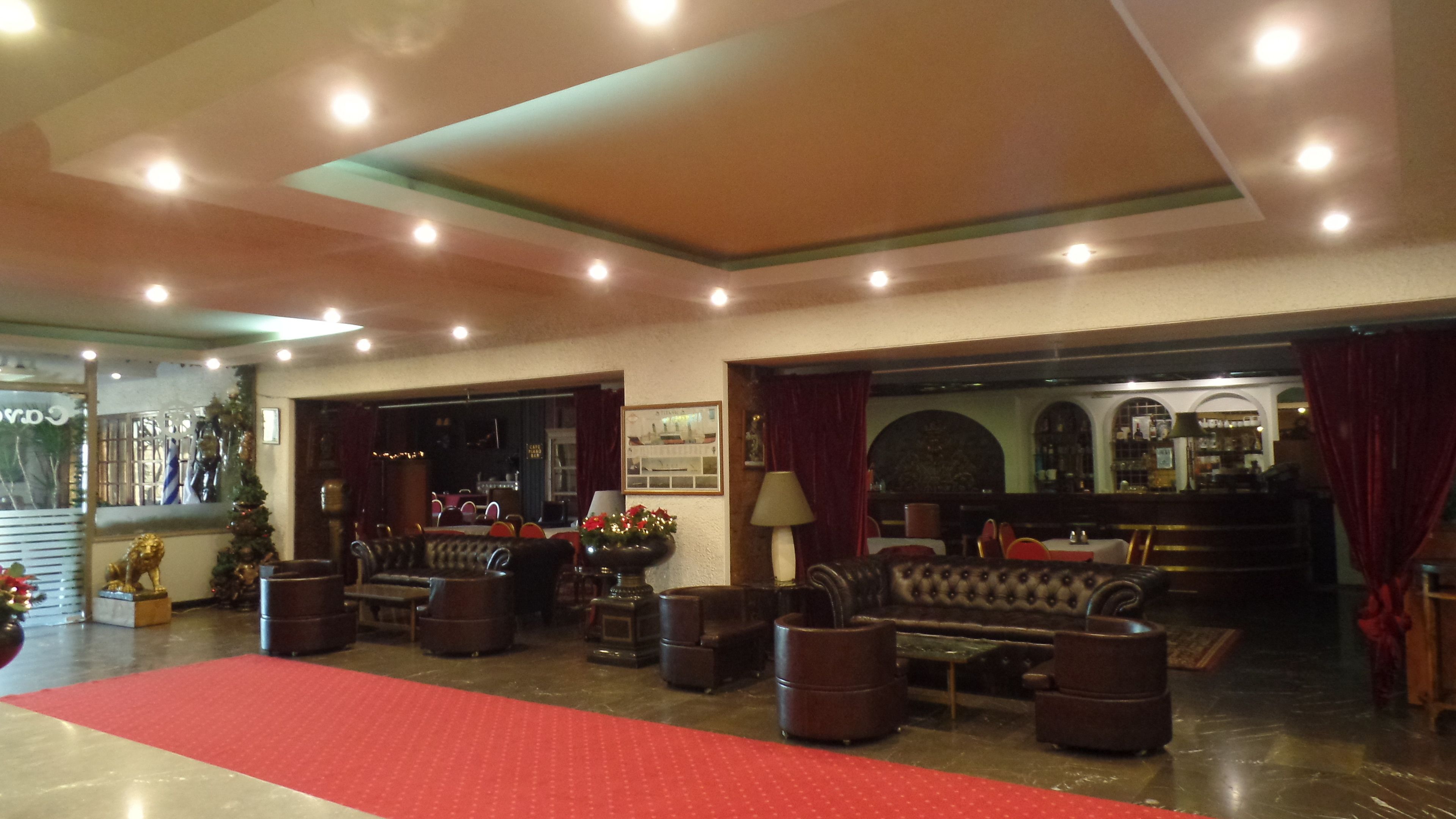 A spacious lobby with a red carpet, leather sofas, and a bar area.
