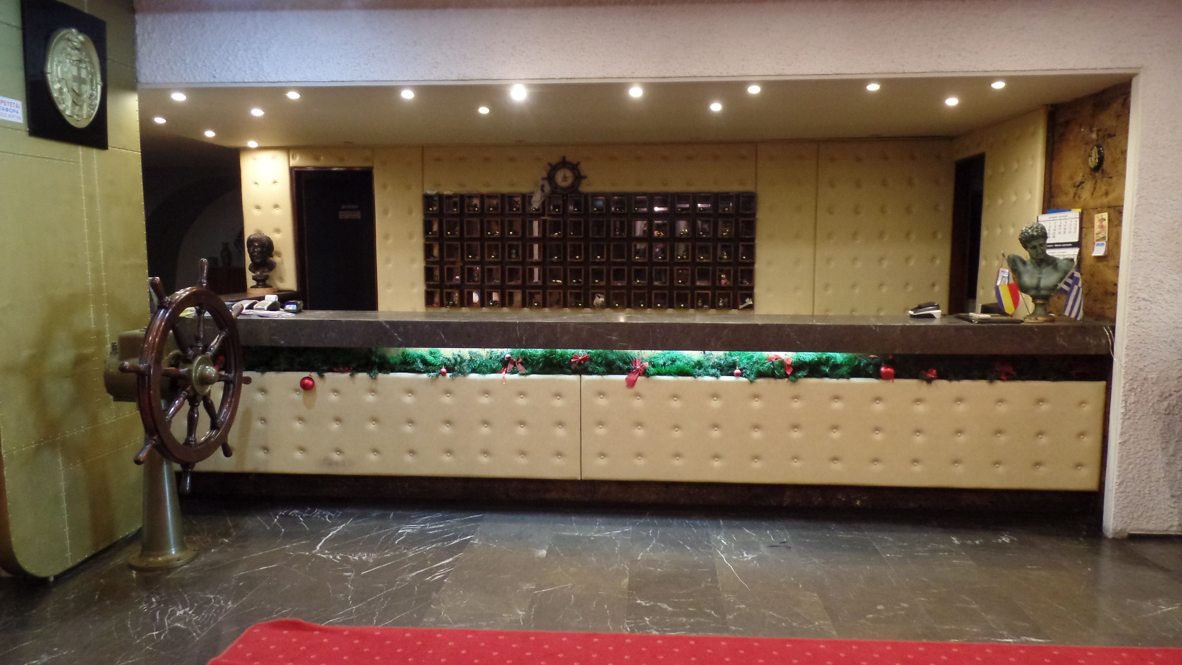 A reception desk with a clock, a ship's wheel, and a wall of framed pictures.