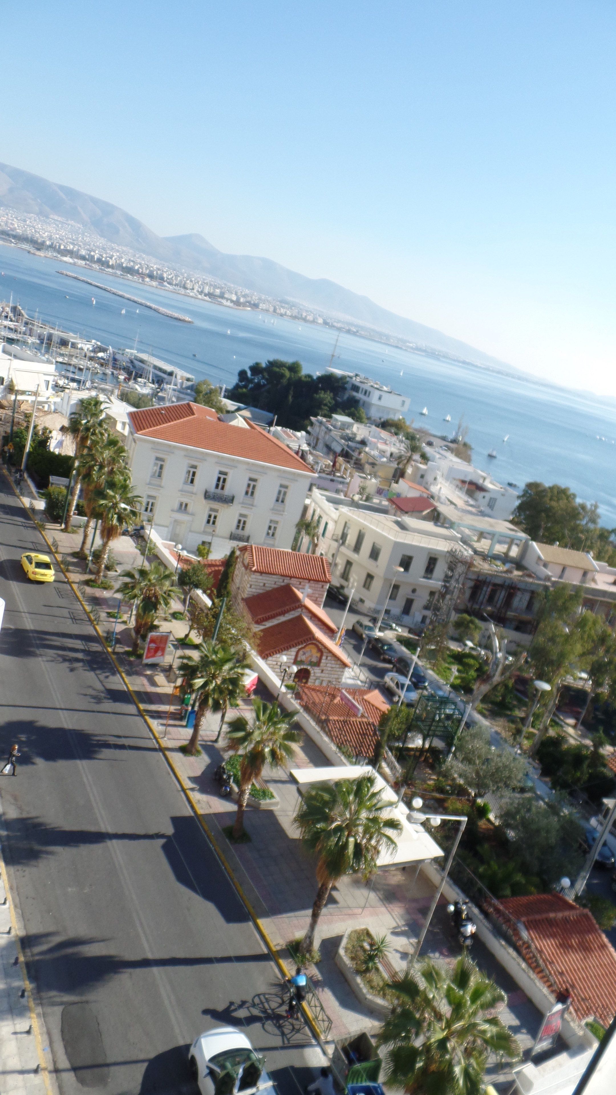 Un paisaje urbano costero con edificios, un puerto deportivo y una vista despejada del mar.