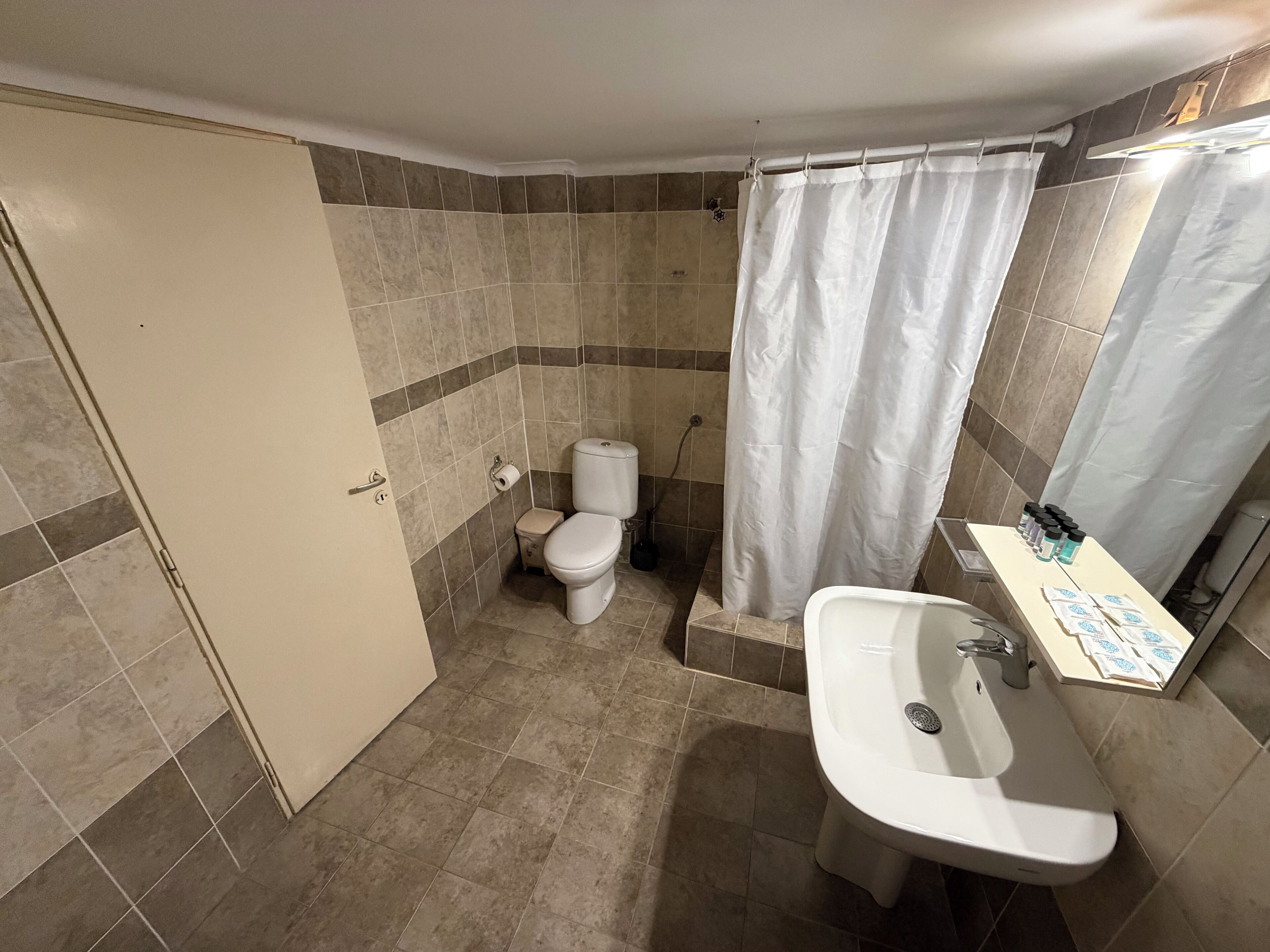 A bathroom with a toilet, shower, and sink.