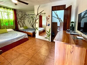 Habitación de hotel con dos camas, un escritorio de madera, un televisor y un baño visible a través de una puerta.