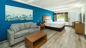 Een moderne hotelkamer met een blauwe accentmuur, een groot bed, een bank, een houten bijzettafeltje en een televisie.