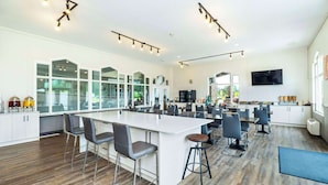Een ruime keuken met een centraal kookeiland, barstoelen en een groot raam dat voor natuurlijk licht zorgt.