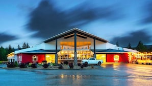 Een modern hotel met een grote glazen gevel, een overdekte ingang en een parkeerplaats.