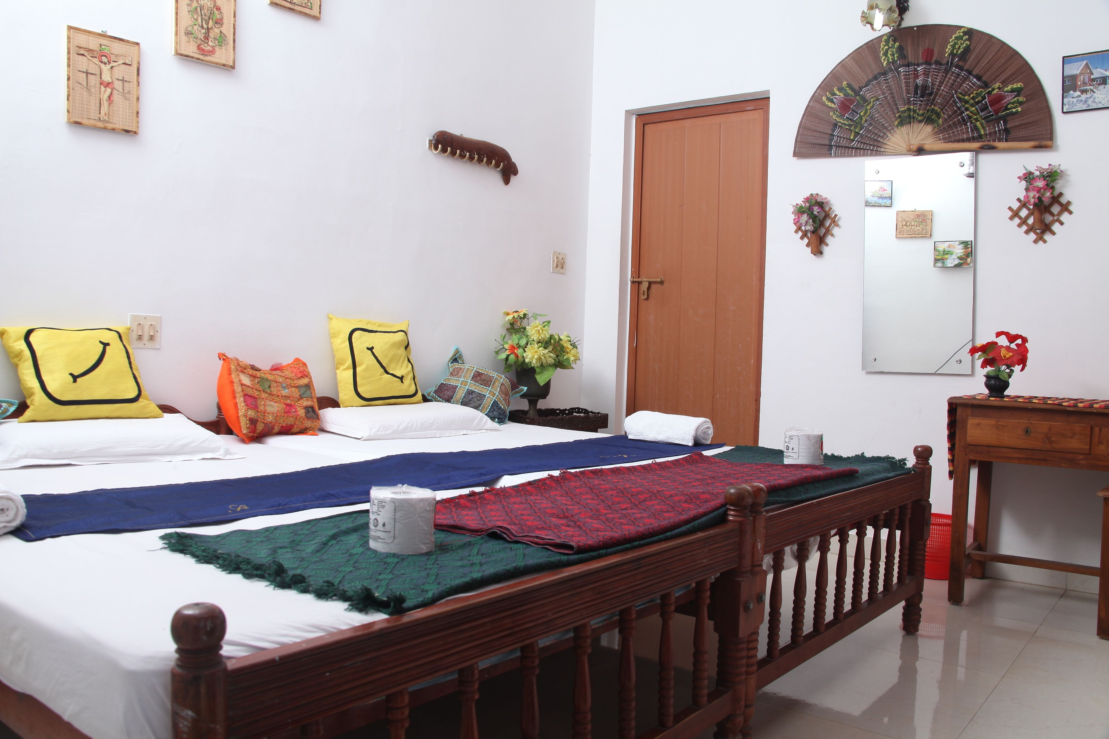 A bedroom with a wooden bed, multiple pillows, a bedside table, a mirror, and a wooden dresser.
