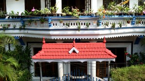 A building with a red roof, white walls, and a blue gate. - Dream Catcher Home Stay (Kochi)
