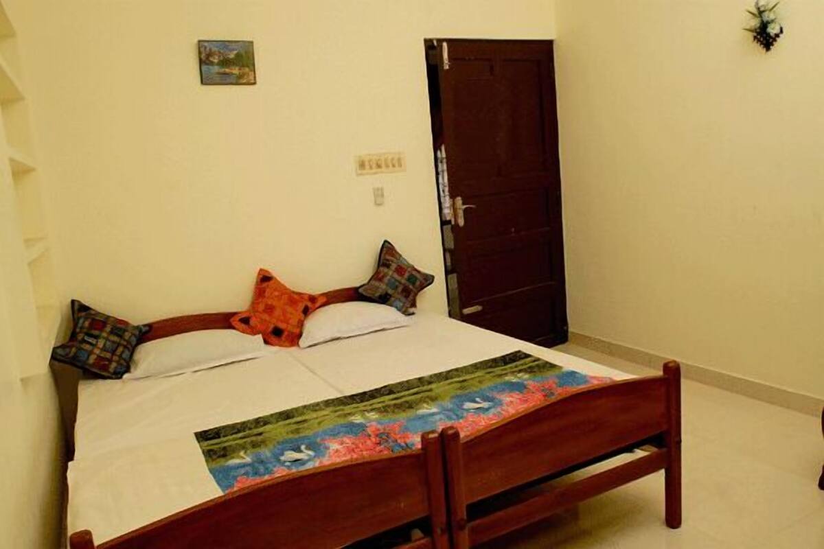 A bed with a floral bedspread, two pillows, and a wooden headboard.