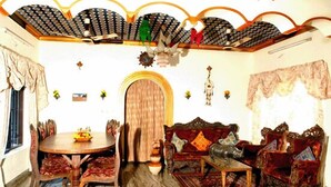 A traditional room with a round wooden dining table, ornate sofas, and a decorative ceiling. - Dream Catcher Home Stay (Kochi)