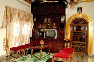 A traditional room with a wooden cabinet, a television, and a red sofa.