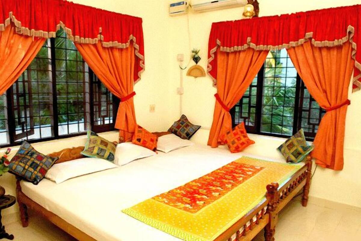 A room with a bed, red curtains, and a window with a view of greenery.
