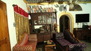 A traditional living room with two patterned sofas, a wooden coffee table, and a bookshelf filled with books. - Dream Catcher Home Stay (Kochi)