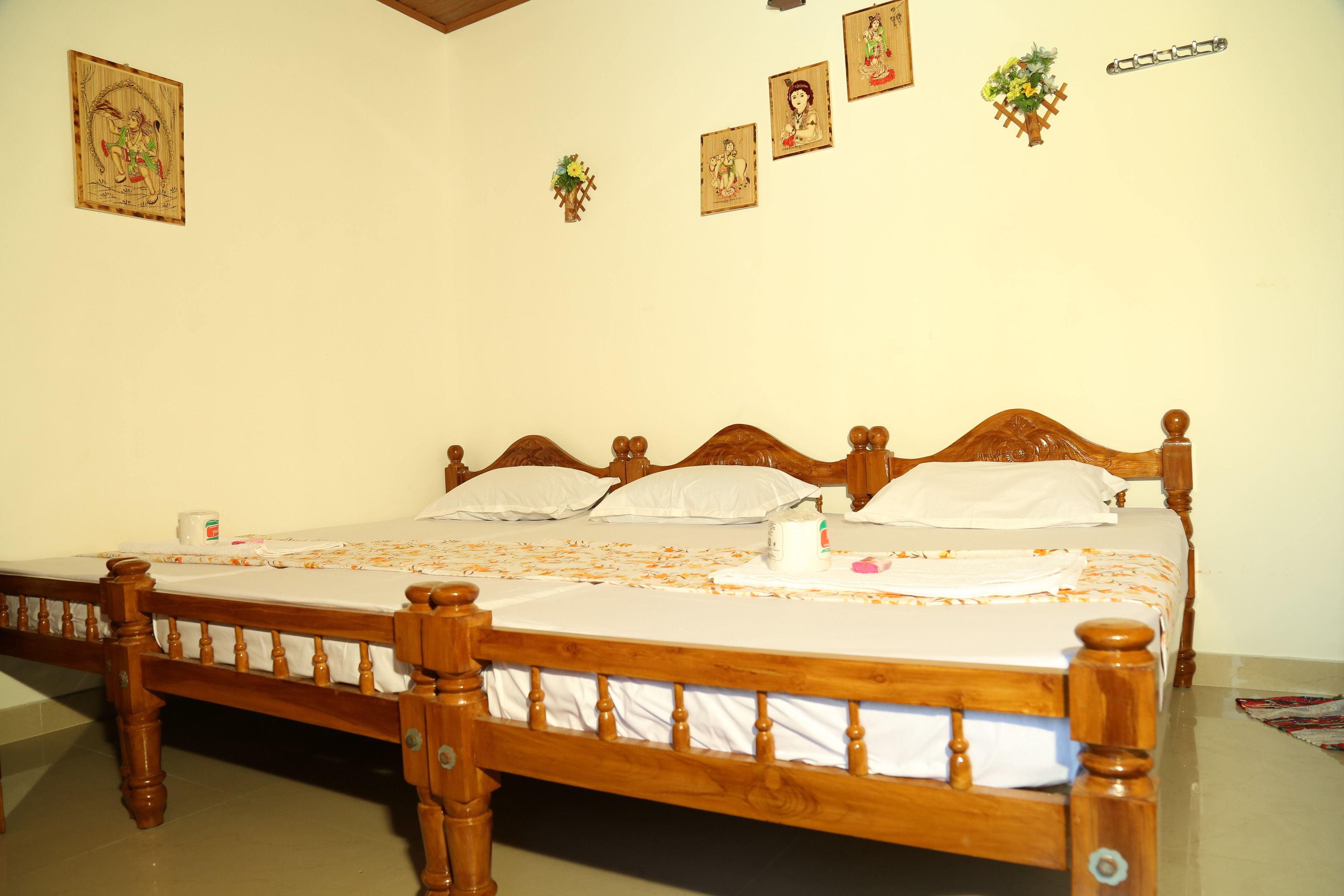 Una cama de madera con ropa blanca, una mesita de noche pequeña y una pared con cuadros enmarcados.