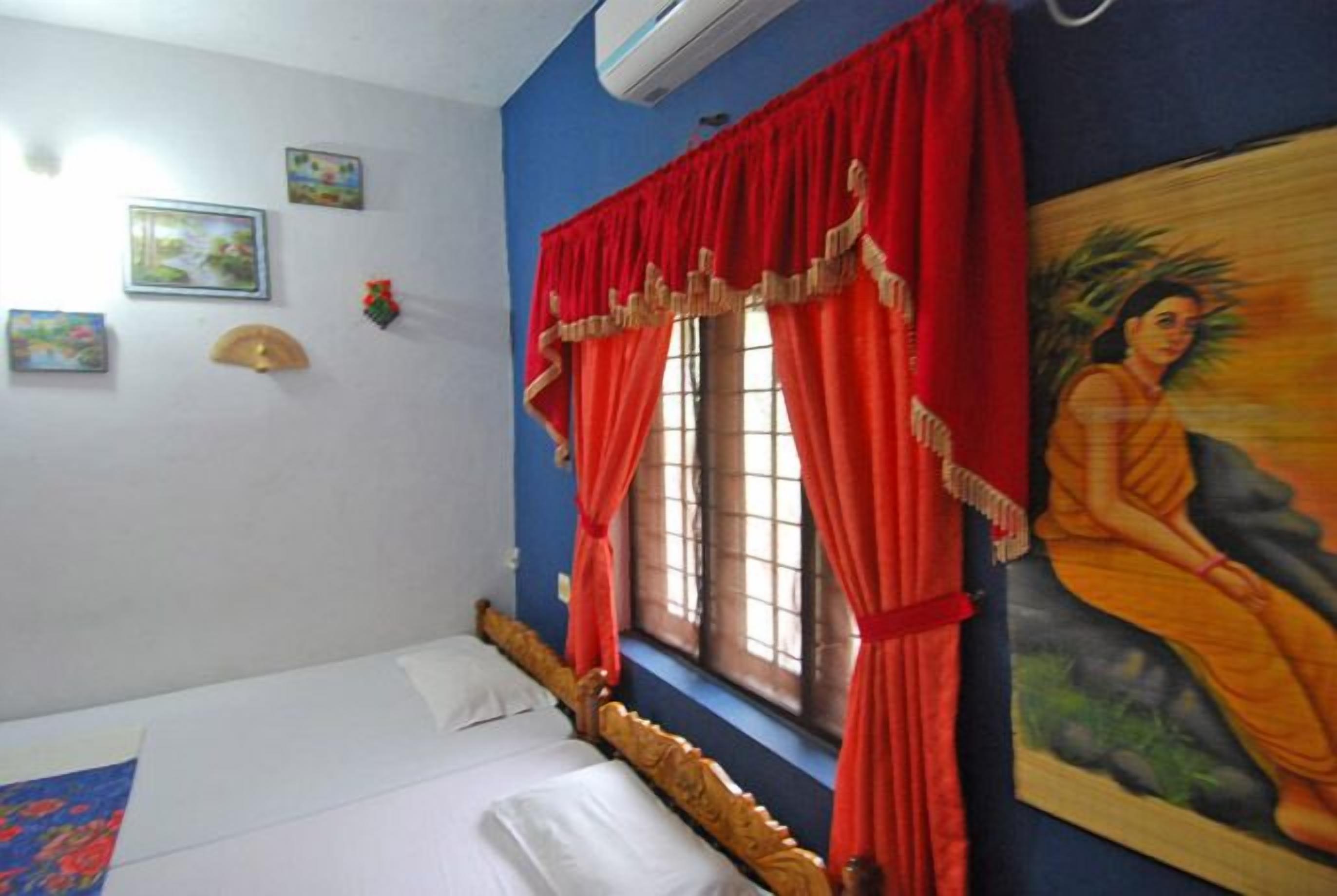 A bedroom with a single bed, a window with red curtains, and a wall-mounted air conditioner.