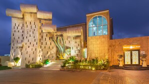 A modern building with a unique architectural design, featuring a large sculpture and a prominent arched window.