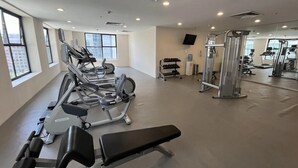 Ein Fitnessstudio mit Laufbändern, Hanteln und einer Spiegelwand.