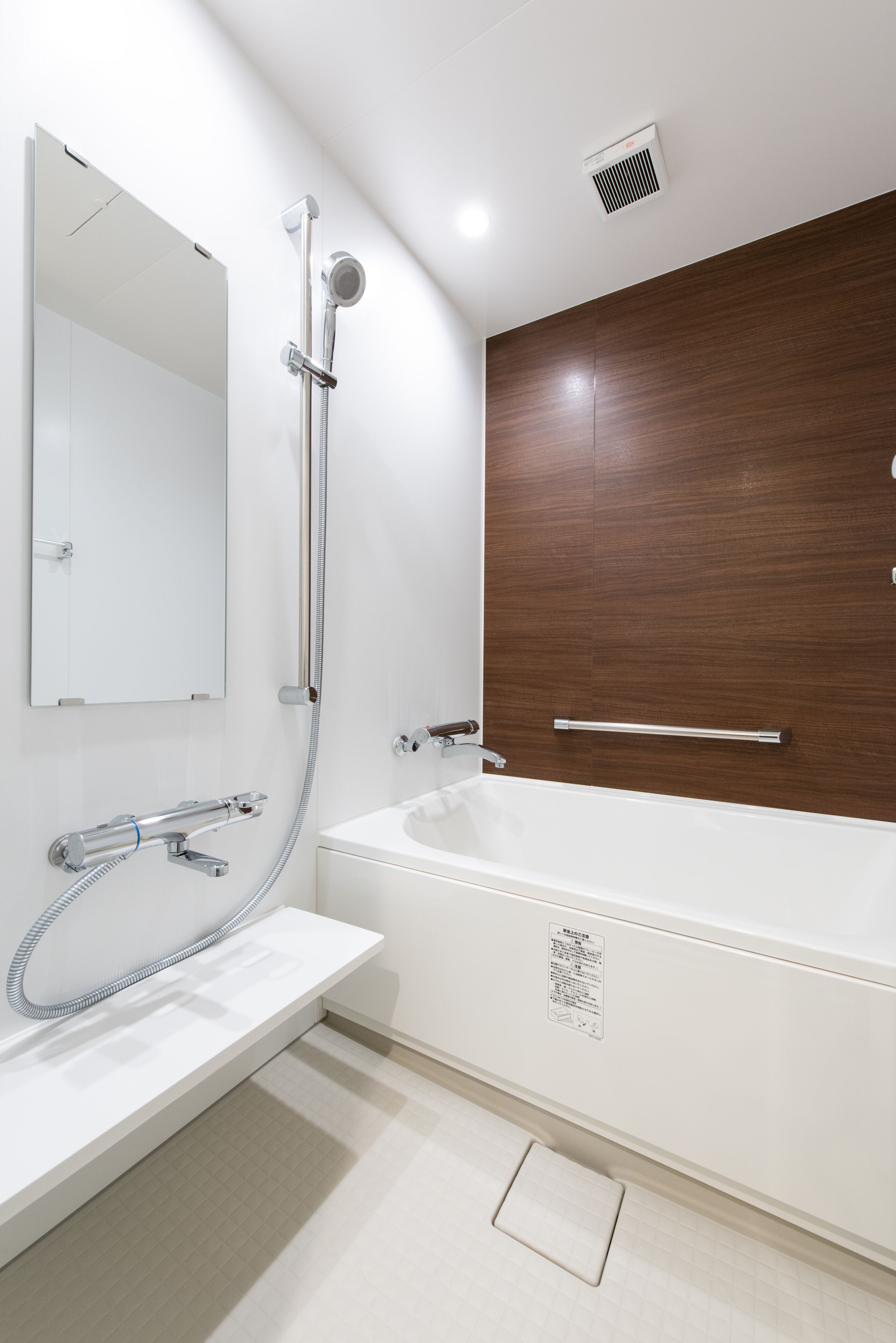 A modern bathroom with a white sink, a large bathtub, a wooden accent wall, and a mirror.