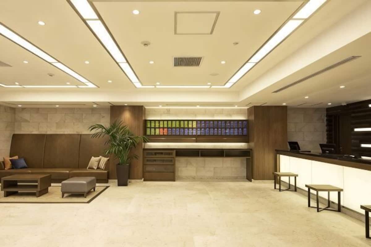 Un hall d'entrée moderne avec un comptoir d'accueil, un espace salon et une plante.