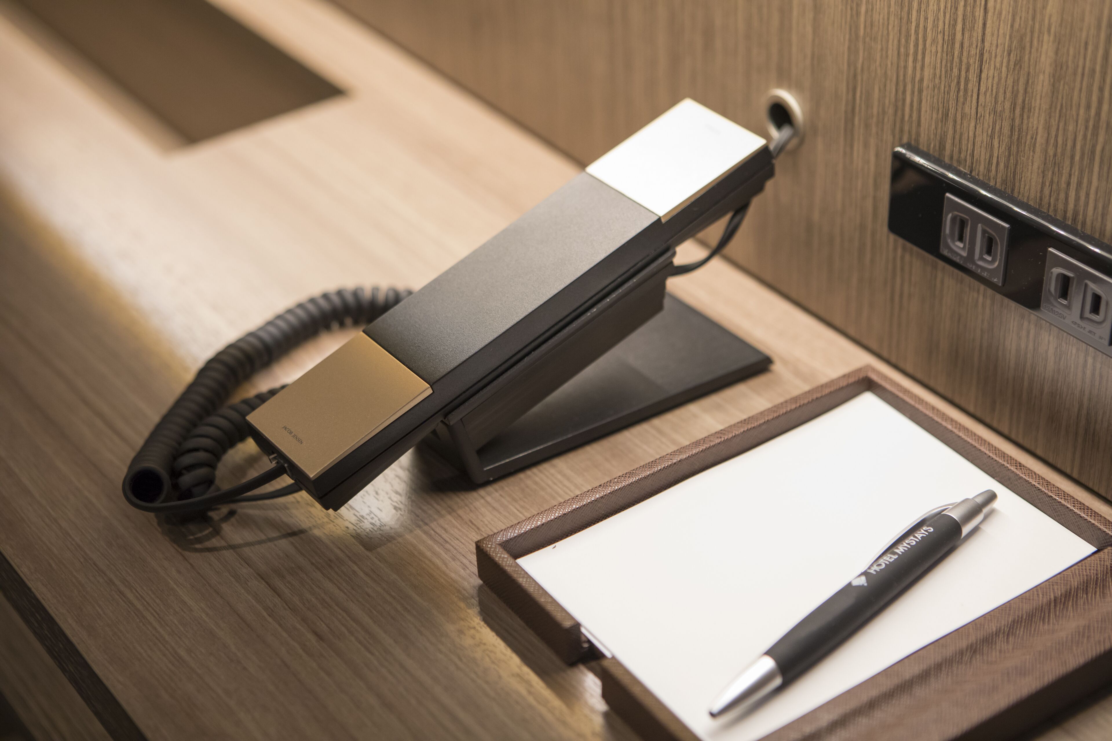 A desk with a telephone, a pen, and a framed paper.