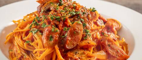 A plate of spaghetti with sausage and tomato sauce, garnished with herbs.