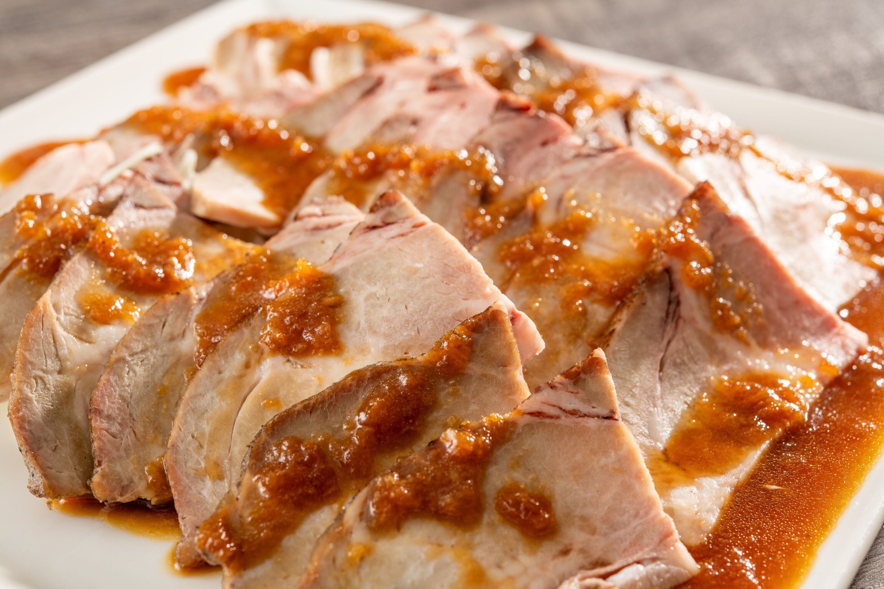 A plate of sliced meat with a glaze.