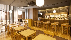 A restaurant interior with wooden tables and chairs, a bar area with a menu, and pendant lighting. - Hotel MyStays Gotanda Station (Tokyo)