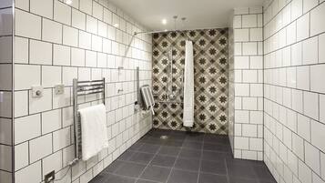 A bathroom with white and patterned tiles, a shower with a star pattern, and a towel rack with a white towel.