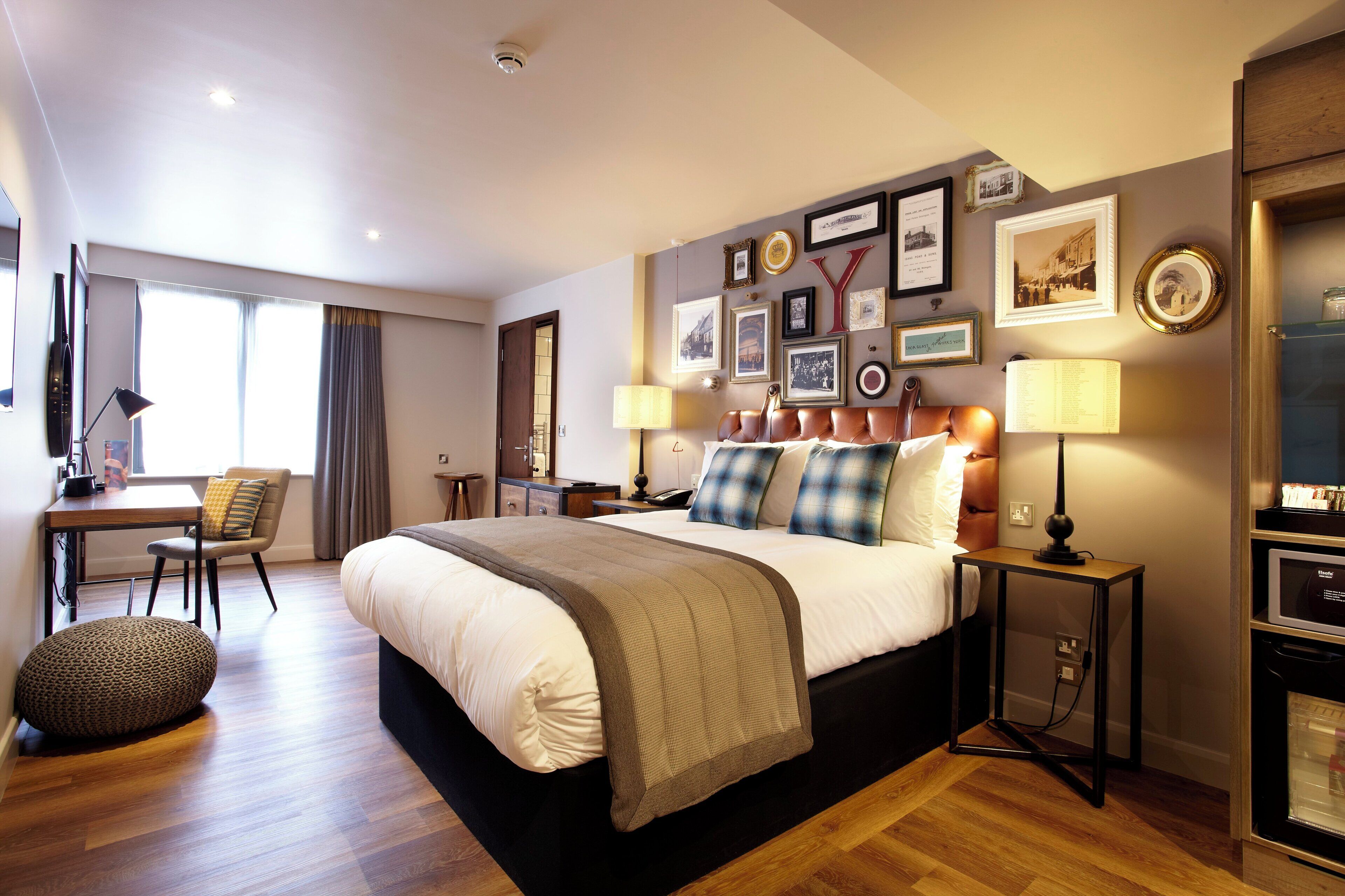 Una habitación de hotel moderna con una cama grande, mesitas de noche, un escritorio y una silla.
