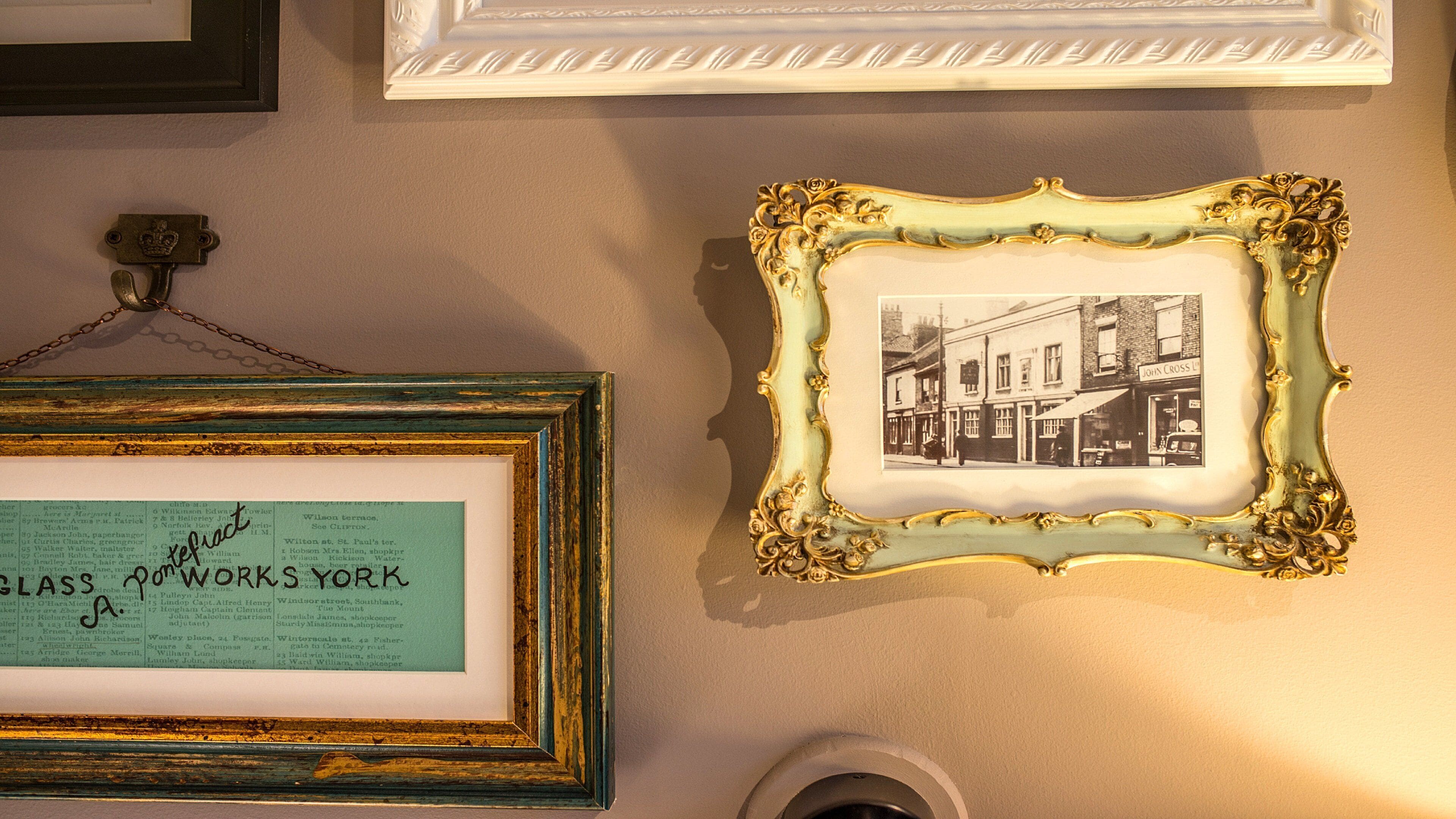 A wall with multiple framed items, including a framed text and a framed photograph.