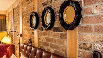 A brick wall with three decorative mirrors and a leather sofa.