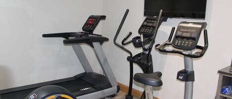 Ett hemmagym med löpband, crosstrainer och motionscykel.