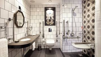 A modern bathroom with a dual sink vanity, a toilet, a shower, and a mirror.